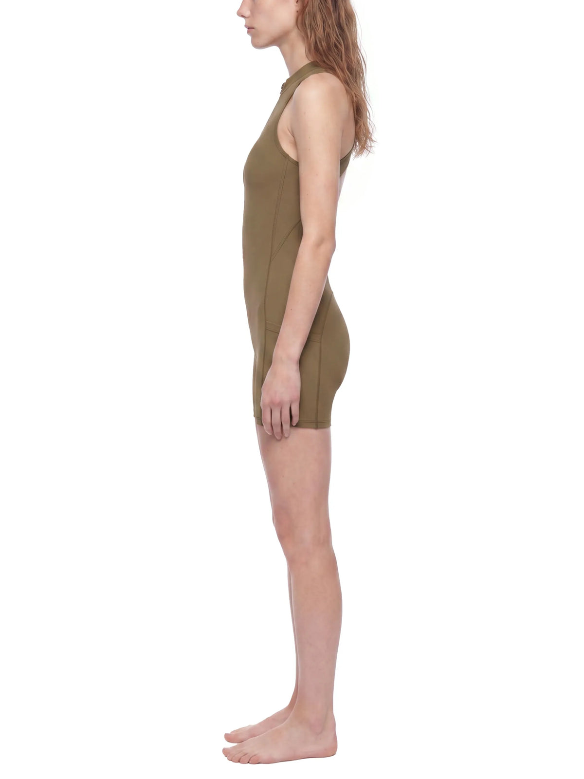 Side view of a model wearing a Quarter-Zip Yoga Romper in olive green, showcasing its athletic fit.